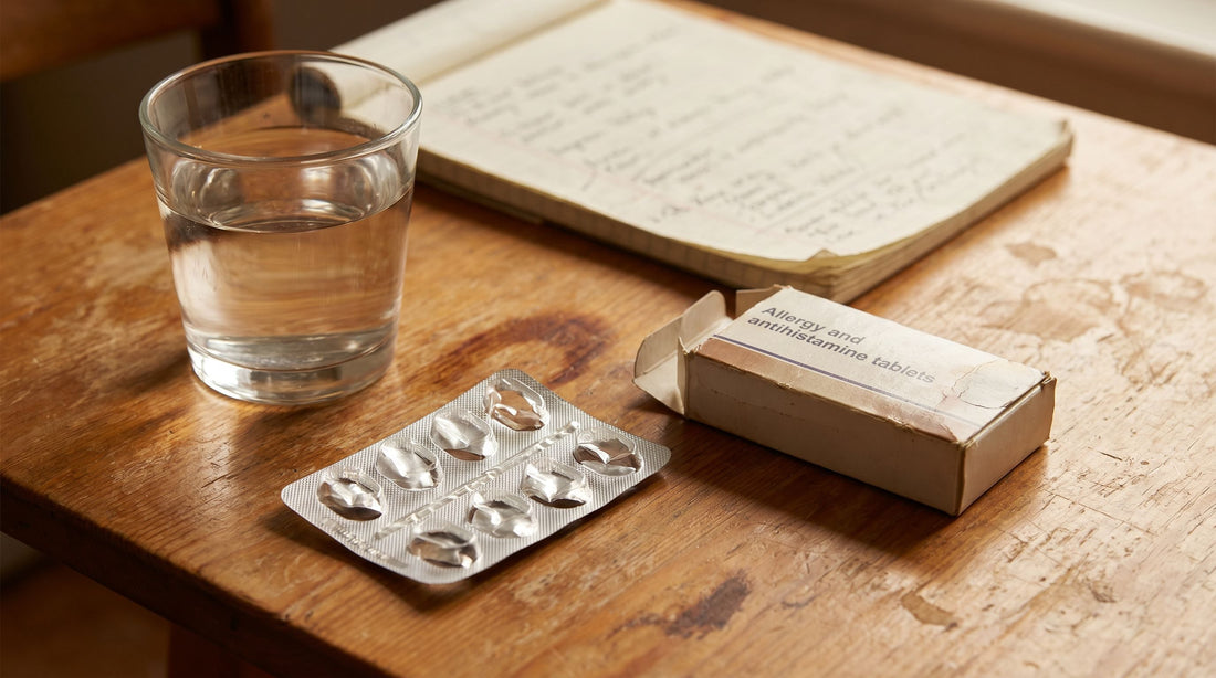 A desk with a glass of water, open pack of throat lozenges, allergy medication, and a notepad representing years of misdiagnosis and failed treatments for silent reflux.